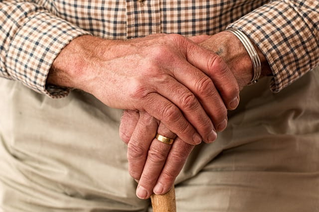 Mains d'une personne âgée sur une canne.