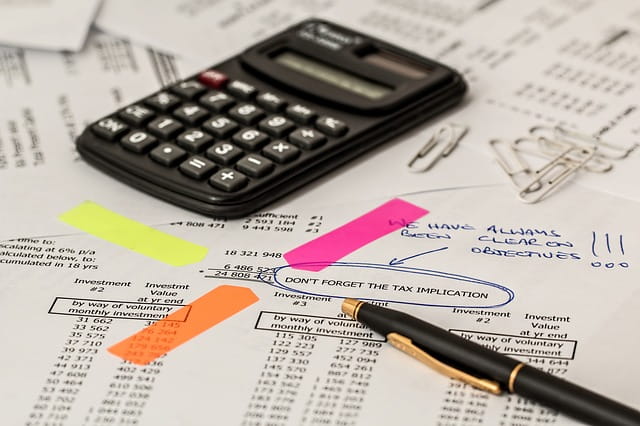 Calcul des impôts sur des papiers avec calculatrice, stylo et notes.