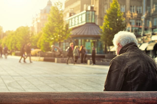 Photographie d'une personne âgée assise sur un banc.