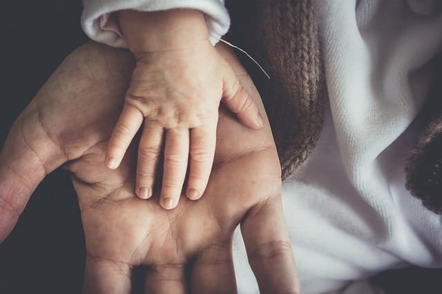 Une main d'enfant posée sur une main d'adulte.