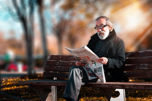 Homme âgé sur un banc qui lit.