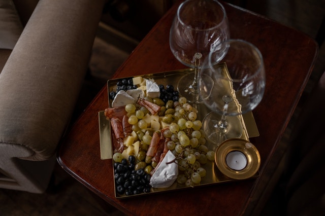 Plateau fruits et charcuterie avec verres de vin.